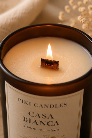 Macro dello stoppino in legno acceso della candela Casa Bianca alla vaniglia Piki Candles